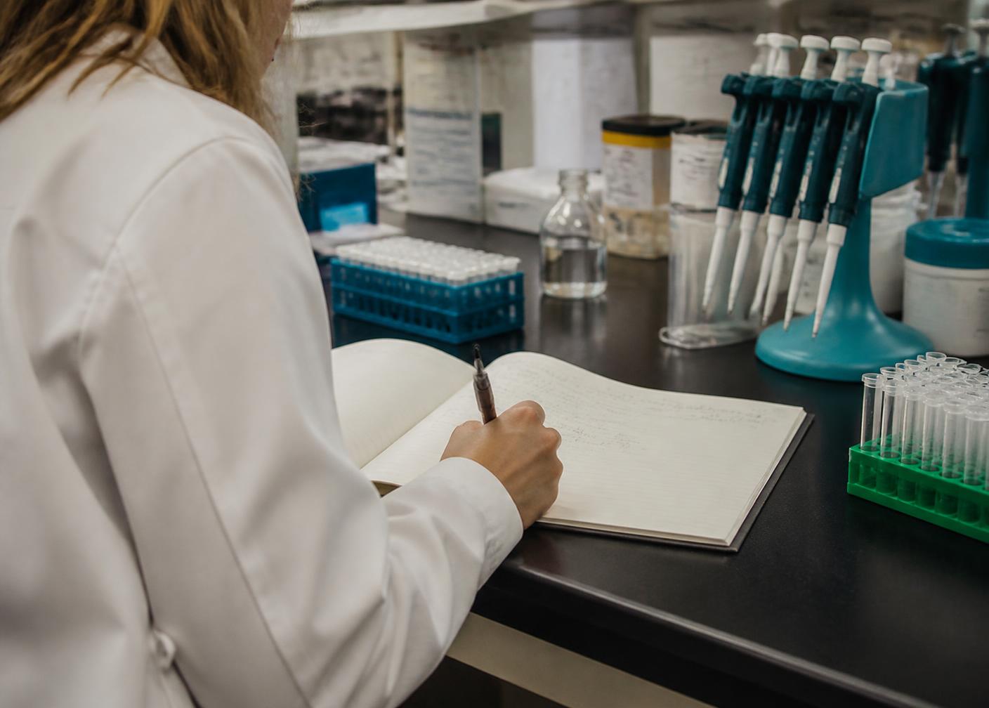 Researcher recording experimental conditions in a bound lab notebook